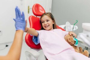 Niña pequeña en odontopediatría saludando al dentista