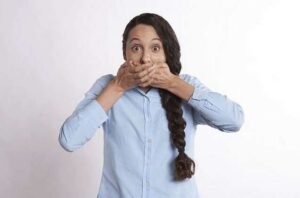 Chica tapándose la boca porque tiene Halitosis. ¿Cuáles son las causas y remedios?