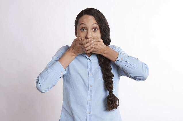 Chica tapándose la boca porque tiene Halitosis. ¿Cuáles son las causas y remedios?